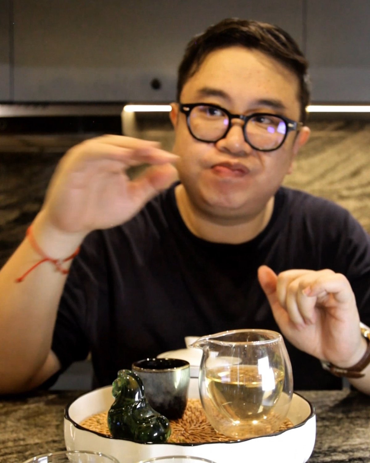 The writer gestures while tasting the sixth infusion, with several earlier cups arranged across the table.