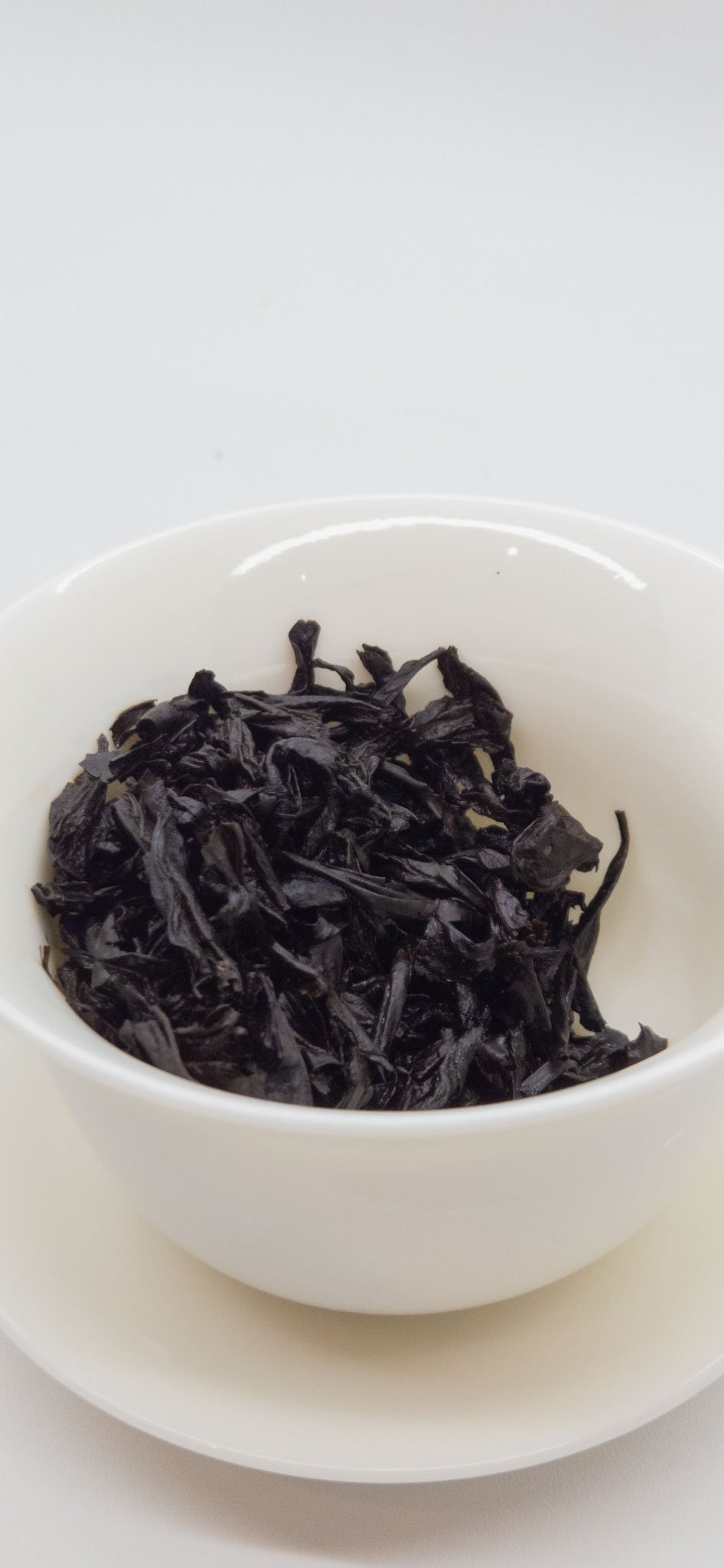 Tea leaves opened after brewing inside a white gaiwan